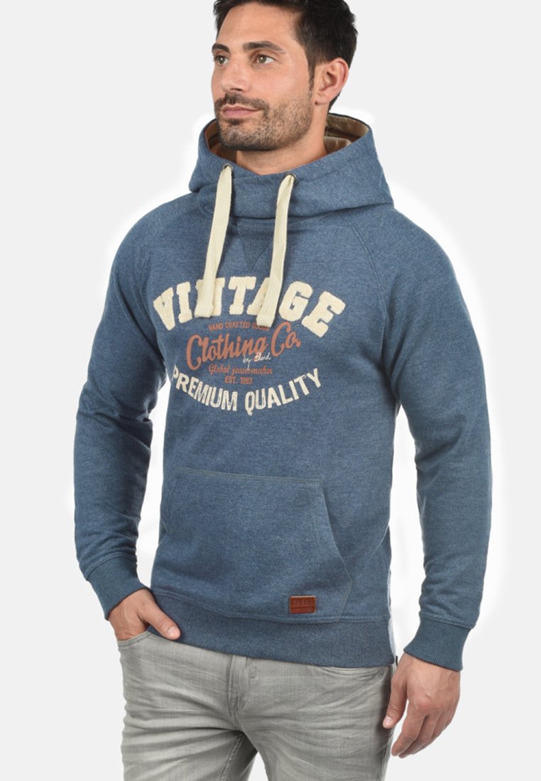 Sudadera azul de tejido suave, con un bolsillo frontal tipo canguro, cordones crema y un diseño impreso de "VINTAGE Clothing Co."