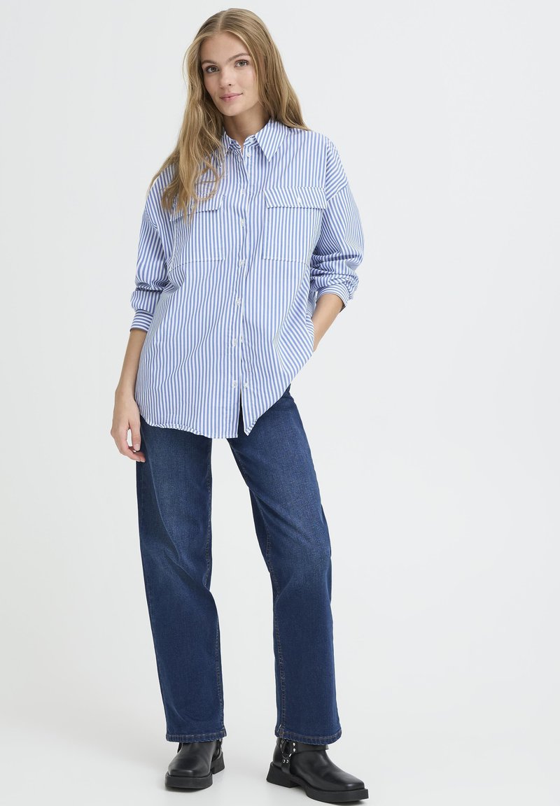 Blue and white striped button-up shirt with two front pockets, paired with dark blue wide-leg jeans and black ankle boots.