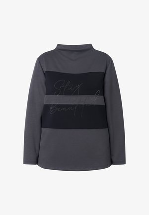 Grå og sort langærmet top med en mock krave, som har en glitrende "Stay Beautiful" tekst i kursiv over ryggen. Materiale i bomuldsblanding.