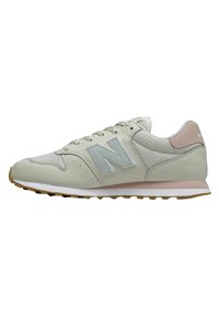 Tenisky New Balance s horní částí z lehké béžové kůže a síťoviny, pastelově růžové akcenty a kontrastní podrážka z gumy. Sportovní design.