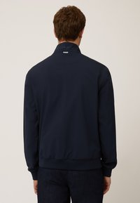 Giacca bomber blu navy in materiale leggero, con colletto rialzato, polsini e fascia in costina. Design semplice, senza motivi o dettagli.