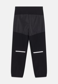 Sorte bukser med en blanding af mat og skinnende stof, med reflekterende horisontale striber nær anklerne og elastiske manchetter.