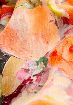 Világos textil, amely élénk narancs, rózsaszín és zöld absztrakt virágmintákkal rendelkezik, puha tapintással és finom fényességgel.