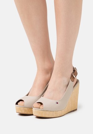 Sandalias de cuña beige con punta abierta, que cuentan con una parte superior de lona, plataforma de yute trenzado y una correa de tobillo ajustable marrón con herrajes de metal.