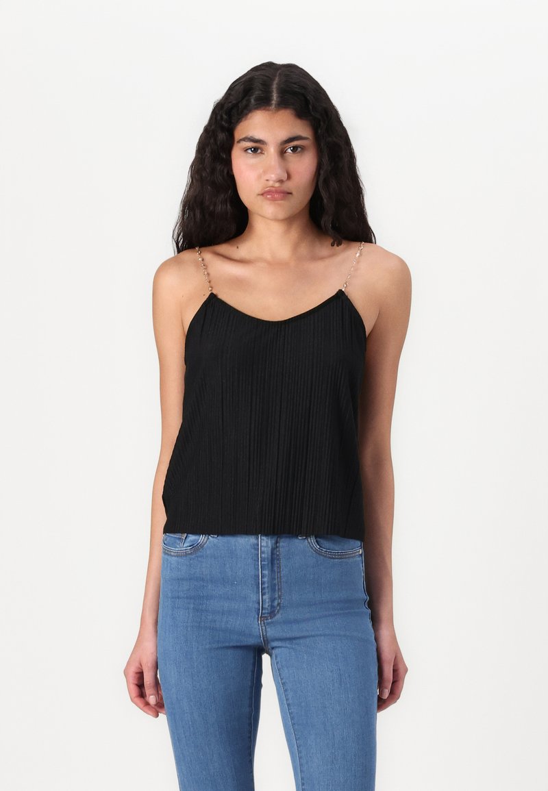 Svart plissert cami med tynne stropper pyntet med perler. Jevn tekstur, semifitt design, brukt med blå høytlivsjeans.