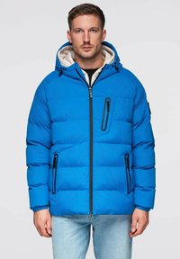 Sininen tikkitakki kiiltävällä pinnalla ja hupulla, jossa mustat vetoketjulliset taskut, etuvetoketju ja joustavat hihansuut.