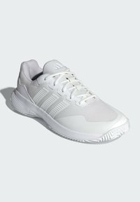 Biele športové topánky s textúrovaným sieťovaným zvrškom, vybavené tromi výraznými pruhmi, šnúrkami a gumovou podrážkou so zúbkovaným vzorom.