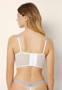 Sutien alb cu panouri din material transparent pe spate, detalii din dantelă albastră pe bretele și închidere cu cârlig și ochi; bikini albastru asortat cu accente din dantelă.