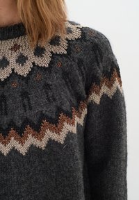 Pulover tricotat de culoare gri închis cu un yoke cu model geometric în bej și marou. Prezintă fibre texturate și un design clasic cu guler rotund.