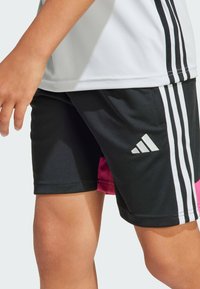 Shorts deportivos negros con rayas blancas y un acento rosa. Hechos de una tela suave y ligera con un logo de Adidas en el costado.