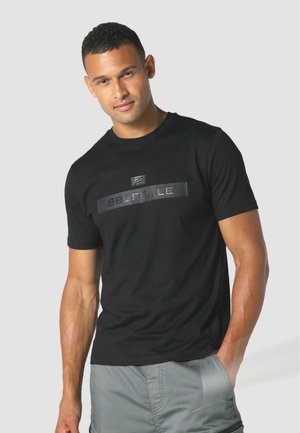 Tricou din bumbac negru cu guler rotund și mâneci scurte, având un logo grafic proeminent din negru și argintiu pe piept.
