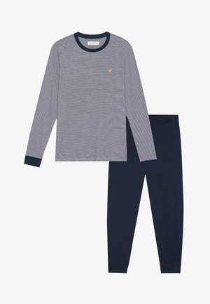 Camiseta de rayas de manga larga en azul marino y blanco, con un cuello redondo azul marino y un pequeño logo amarillo, combinada con pantalones sólidos azul marino.