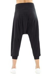 Pantalons harems noirs avec une taille élastique, coupe ample et poignets ajustés. Fabriqués en tissu doux et léger pour le confort et la liberté de mouvement.