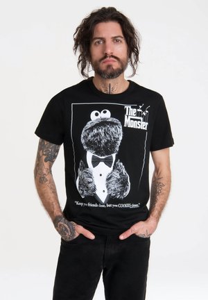Sort t-shirt med grafik af en pelsklædt karakter i smokin, med hvid tekst nedenunder: "Hold dine venner tæt, men dine COOKIES tættere."