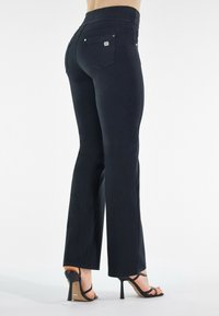 Musta leveälahkeinen farkut korkealla vyötäröllä, joissa on kaksi takataskua ja metallikoristeita. Silkkinen pinta, jossa on hieno kiilto. Yhdistetty mustien korkeakorkoisten kenkien kanssa.