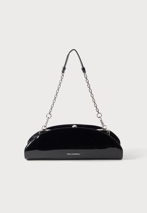 Sac à main noir brillant avec une bandoulière chaîne argentée et un petit logo KARL LAGERFELD sur le devant, sur un fond clair uni.