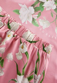 Pink fabric featuring large white floral patterns, with a gathered elastic waistband and soft, smooth texture. Branding is subtly printed.