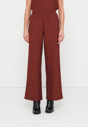 Nohavice s širokými nohavicami z bohatej bordovej látky s textúrovaným diamantovým vzorom. Sú vybavené elastickým pásom a k nim patrí pár čiernych členkových topánok.