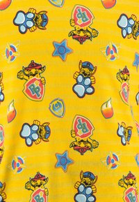Tejido amarillo con divertidos personajes de dibujos animados y distintivos de colores brillantes. Los patrones incluyen estrellas y huellas de patas. Textura suave.