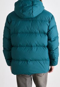 Veste matelassée bleu sarcelle avec un design rembourré, dotée d'une capuche et d'une texture matelassée horizontale. Vue de dos montrant peu de détails.