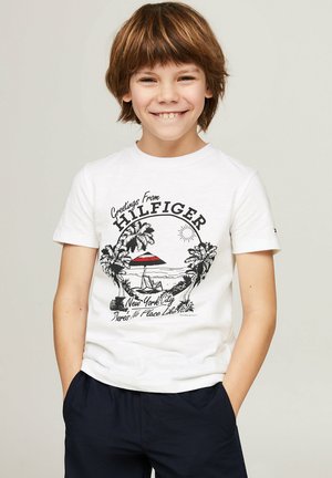 Camiseta de algodón blanca con un estampado gráfico de una escena de playa con palmeras y una sombrilla roja, diseñada con mangas cortas.