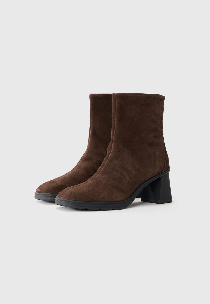 Bottines en daim marron avec un design épuré, des pointes arrondies et un talon épais noir. Présentent une construction sans couture et une surface texturée.