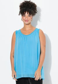 Ljusblå ärmlös topp med rund halsringning, plisseringar framtill och en luftig silhuett, tillverkad av ett mjukt, lätt tyg.