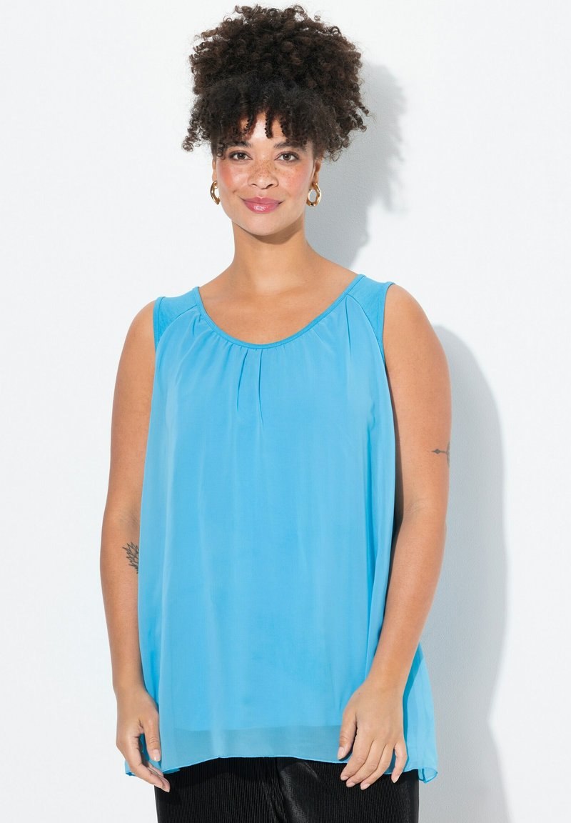Ljusblå ärmlös topp med rund halsringning, plisseringar framtill och en luftig silhuett, tillverkad av ett mjukt, lätt tyg.