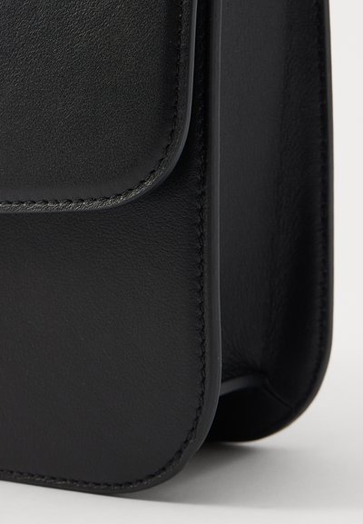 Saco de couro preto com textura lisa, bordas arredondadas e detalhes de costura sutis. Apresenta um fecho de aba e um design slim e compacto.