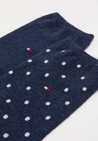Marinblå strumpor med vita prickar, med en liten röd, vit och blå logotyp. Mjuk textur och standard längd av crew-strumpor.