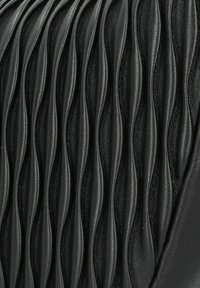 Cuero negro texturizado que presenta pliegues ondulados verticales, creando un patrón de crestas y valles. Acabado liso con un sutil brillo.