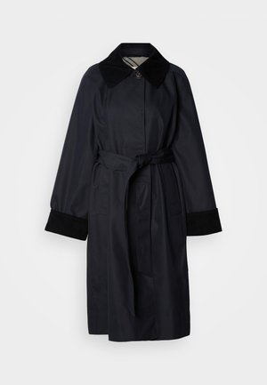 Tume sinine trenssülikond suure kraega, vööümbrisega ja mustade fliiskangasvarrukatega. Sellel on elegantselt minimalistlik disain ja nööpkinnitus.