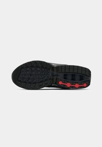 Black athletic shoe sole, featuring textured rubber, a visible air pocket, and red accent buttons arranged along the side.
