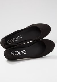 Ballerines en daim noir avec bout rond et texture douce. La semelle intérieure présente un marquage argenté, « &OD » et « even » imprimés en évidence.