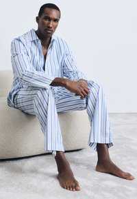 Set de pijama ușor, cu dungi albastre și albe, având o cămașă cu guler și închidere cu nasturi, împreună cu pantaloni confortabili, confecționați dintr-un material moale.