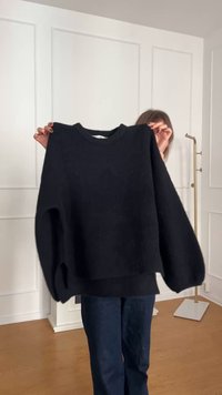 Černý pletený svetr s kulatým výstřihem, spadlými rameny a oversized střihem, který má texturovanou tkaninu a žebrovaný lem.