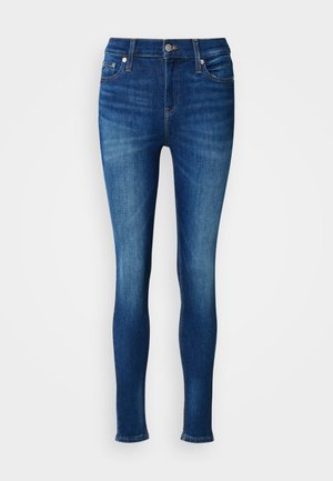 Mørkeblå skinny jeans laget av denim, med klassisk midje, fem lommer og subtil falming langs bena.