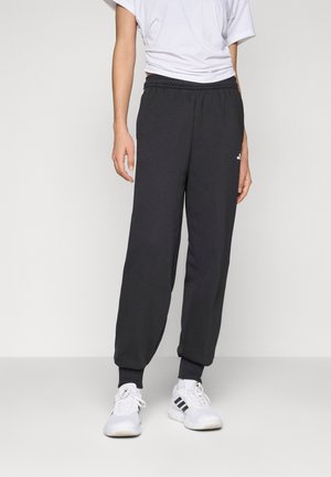 Sorte sweatpants med elastisk midjebånd og mansjetter, laget av myk stoff. En liten hvit logo er synlig på venstre lår.