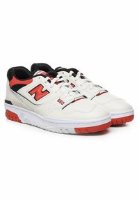 Vita lädersneakers med svarta och röda accenter. Har perforerade sidor, vit gummisula och en framträdande 'N'-logotyp på sidan.