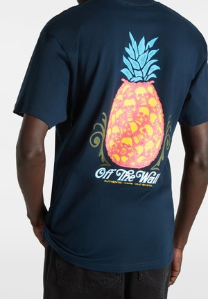 T-shirt en coton bleu marine avec un grand graphisme coloré d'ananas agrémenté de crânes. Texte en bas indiquant "Off The Wall." Manches courtes.