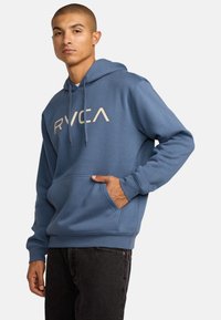 Felpa blu in cotone con tasca a marsupio, cappuccio regolabile con cordino e logo stampato "RVCA" in un colore a contrasto.