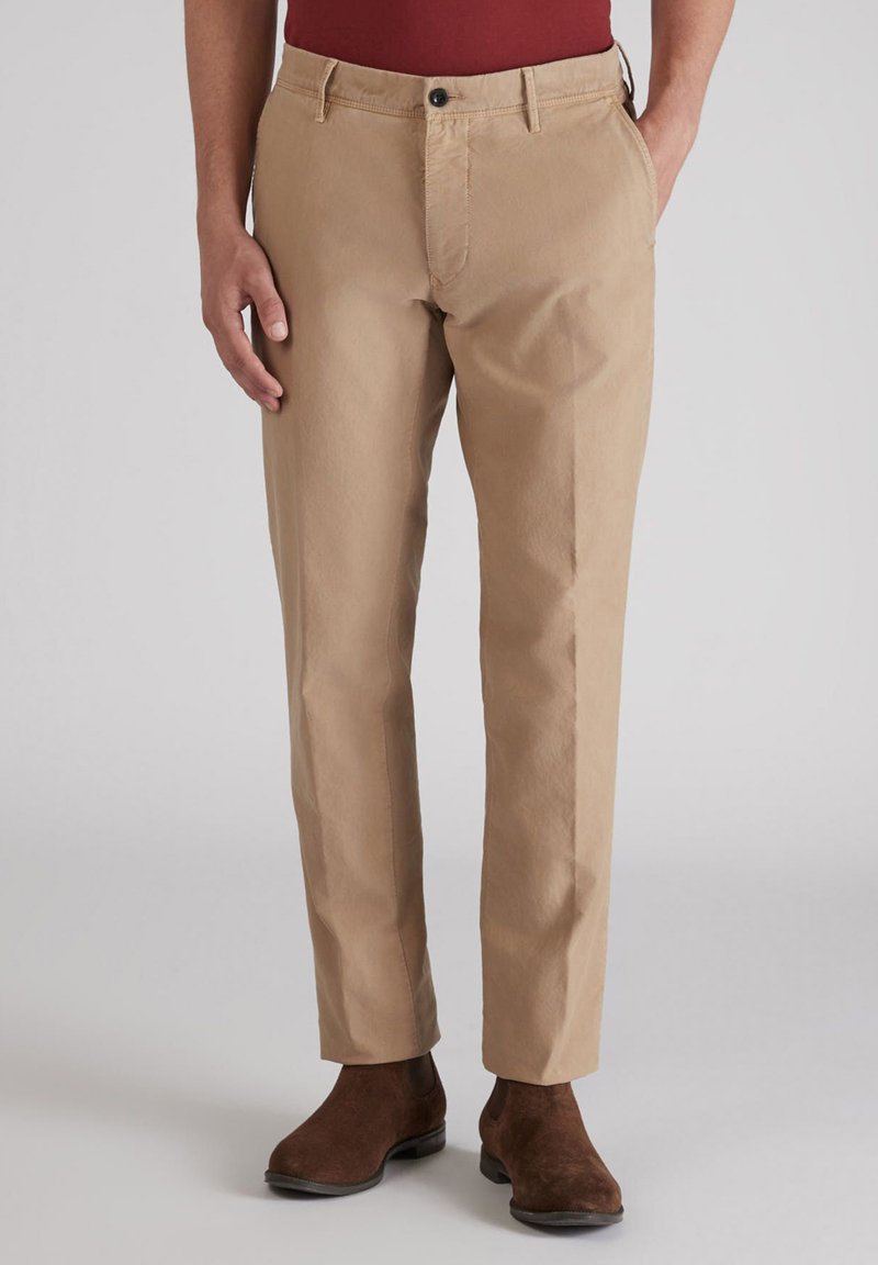 Beżowe bawełniane spodnie o prostym kroju, z zapięciem na guziki z przodu i kieszeniami bocznymi. Noszone z ciemnobrązowymi zamszowymi botkami.