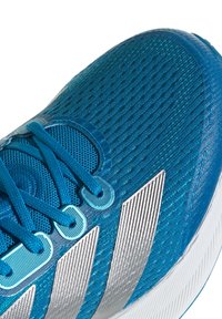 Scarpa da corsa con tomaia blu testurizzata, strisce argentate e lacci blu. Presenta un design leggero e materiale in mesh traspirante.