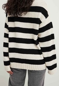 Schwarz-cream gestreifter Strickpullover mit geripptem Saum und langen Ärmeln, der einen lockeren Schnitt und eine weiche Textur aufweist.