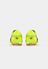 Botas de fútbol amarillas brillantes con acentos negros, que cuentan con un diseño ligero, parte superior texturizada y tacos con punta naranja.
