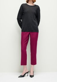 Musta pitkähihaisen neulepusero, pyöreä pääntie, yhdistetty fuksianvärisiin lyhytlahkeisiin housuihin. Asun täydentävät mustat korkokengät.