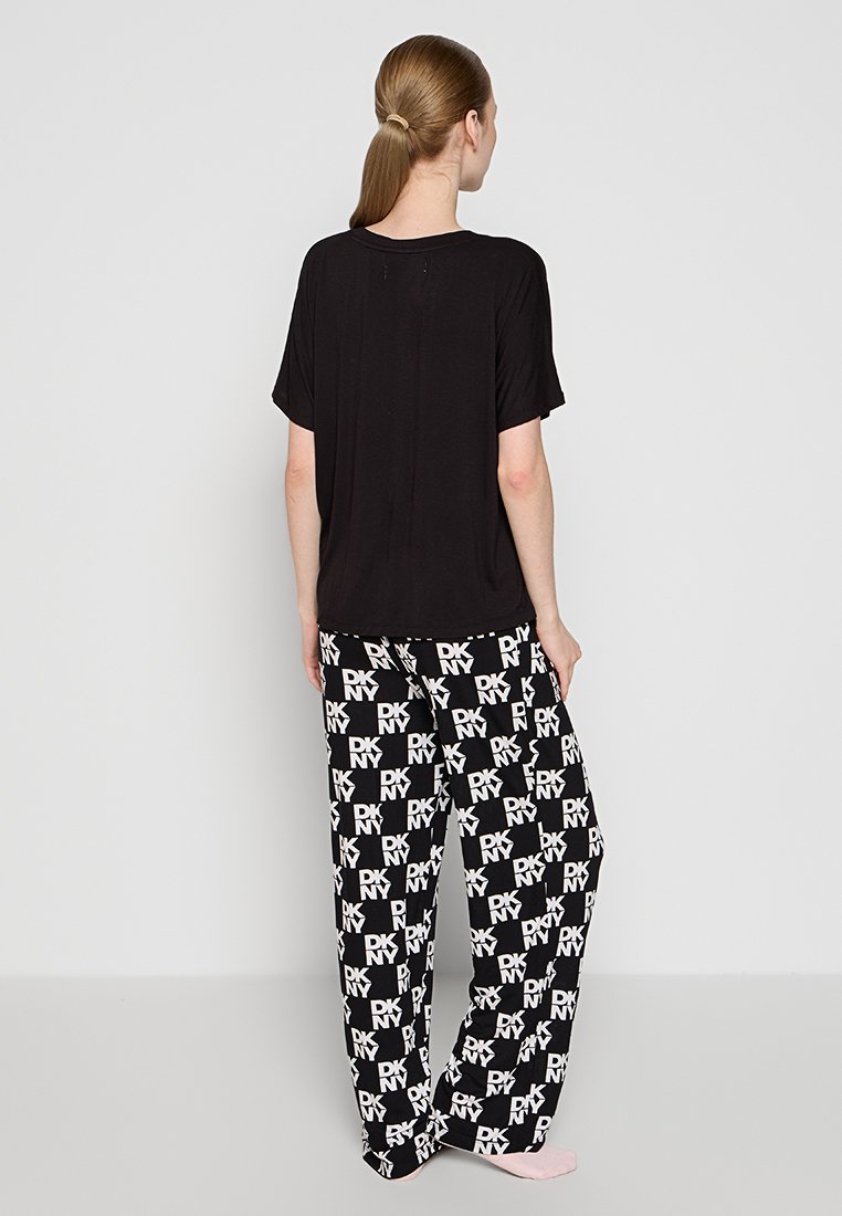 Czarna koszulka krótki rękaw w połączeniu z czarnymi i białymi spodniami piżamowymi w wzór z powtarzającym się logo w odważnym kroju.