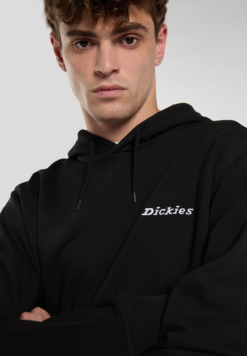 Felpa con cappuccio nera con logo "Dickies" ricamato in bianco. Realizzata in tessuto strutturato, con vestibilità standard e cappuccio con coulisse regolabile.
