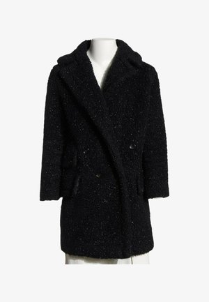 Manteau d'hiver noir texturé à double boutonnage avec larges revers et manches longues présenté sur un buste de mannequin blanc.