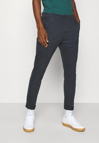 Chino-bukser i dyb navy, tapered fit med opbrettede ben. Fremstillet af letvægtsstof, med sidelommer og knaplukning.